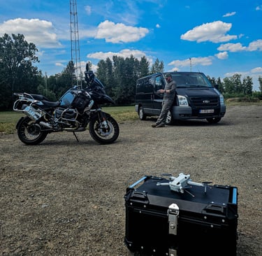 Dronekoffer, motorfiets en bestelwagen staan klaar voor drone-inspectie op locatie met lichtmast op de achtergrond