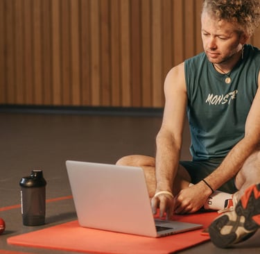 a man sitting on a mat with a laptop