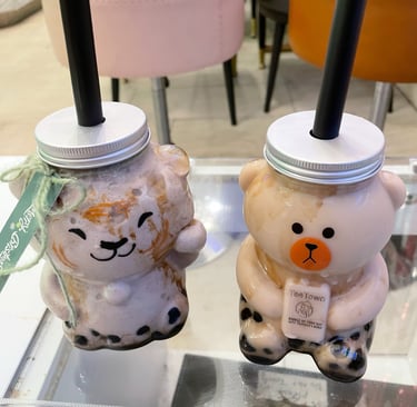 two cups of brown sugar milk tea with boba in animal-shaped cups on a table