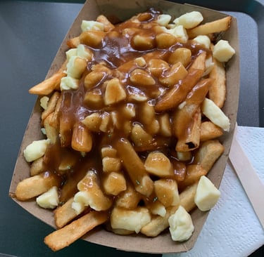A large boat of Poutine: French fries covered in white cheese curds and brown gravy