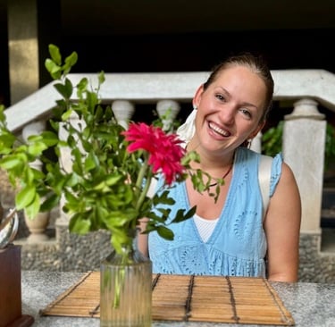 an image of Alena Booth smiling next to Red flowers in India