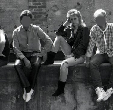 Black and white image of a young woman sitting on a wall with her four male band mates 