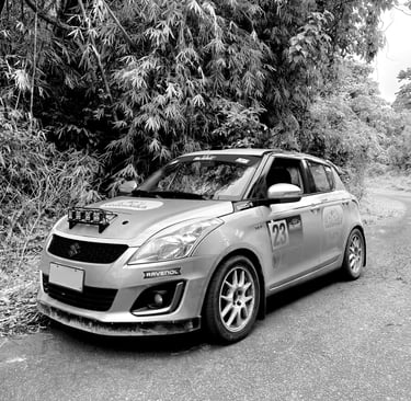 Rally car parked on an empty road with shrubbery and trees in the background