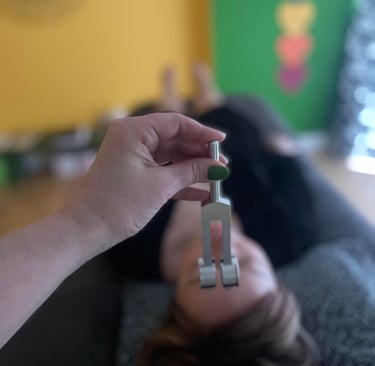 A hand holding a tuning fork during a sound therapy session