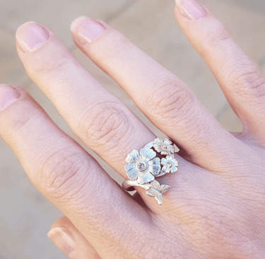 a woman's hand holding a ring with flowers
