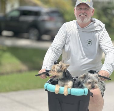 a man riding a bicycle with two dogs in a basket