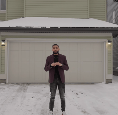 a man standing in front of a house in the snow