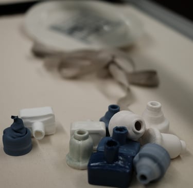 A group of small porcelain ink bottles,, in white and blue, are tumbled together in a display case