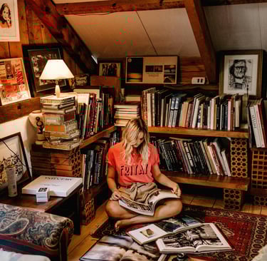 Young woman in attic, with bookshelves, reading a book