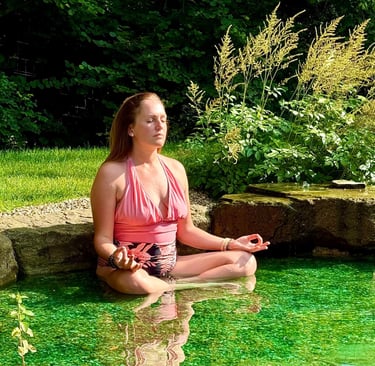 A picture of Alena Booth meditating in a natural lake in UK