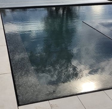 a perimeter flow pool with an automatic pool cover and a sky view 