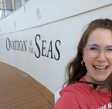 A woman smiling by the side of a Royal Caribbean ship that says Ovation of the Seas