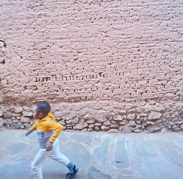 Child running in front of an earthen wall in ksar Amzrou (Zagora) southern Morocco