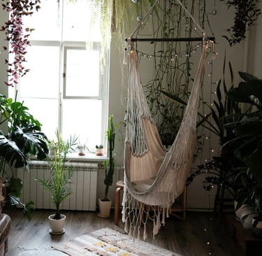 Fauteuil suspendu style bohème devant une fenêtre, nombreuses plantes