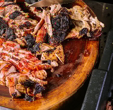 a person cutting a large amount of meat on a cutting board