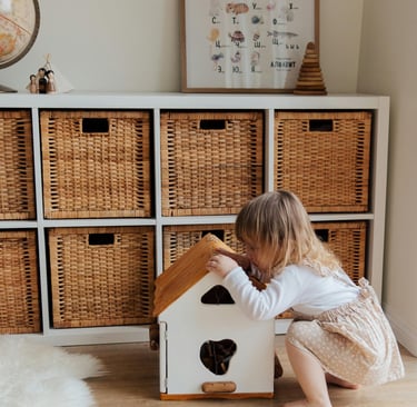 Little girl with play house in front of IKEA Kallax unit with wicker baskets