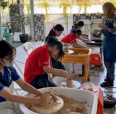 a group of students shaping out clay on pottery wheels