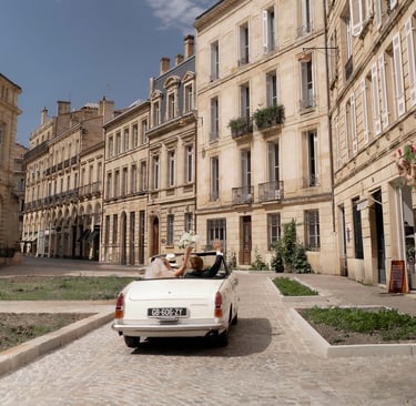a white car driving down a cobblestone street wedding in Bordeaux