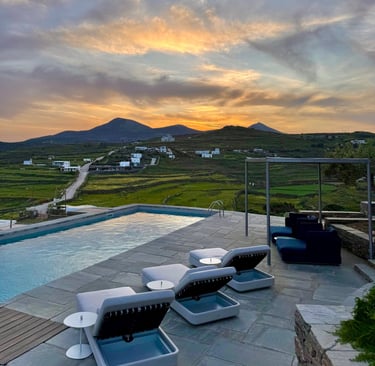 View over the pool onto green hills and small buildings in the distance.