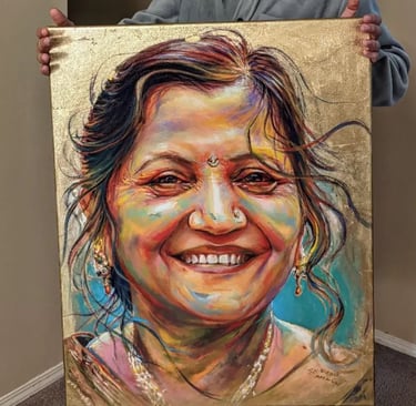 Artist S.K. Gusani holding a memorial painting of a smiling woman, gold leaf, portrait art