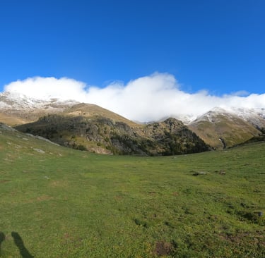 View of Mount Puigmal with green slopes in the foreground and snow-covered peaks in the background i