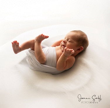 Maleństwo owinięte w delikatny owijacz sesja noworodkowa w studio.