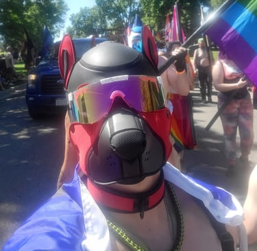 A man marching in a Pride parade wearing a pup mask.