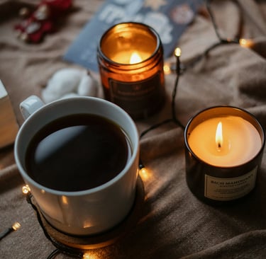 Taza de café caliente rodeada de velas y luces cálidas, evocando bienestar, calma y el ritual person