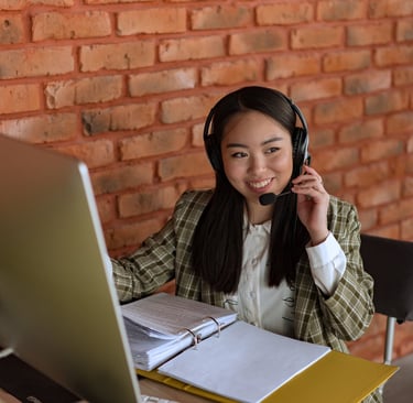 a woman in a plaid shirt and headphones on a laptop