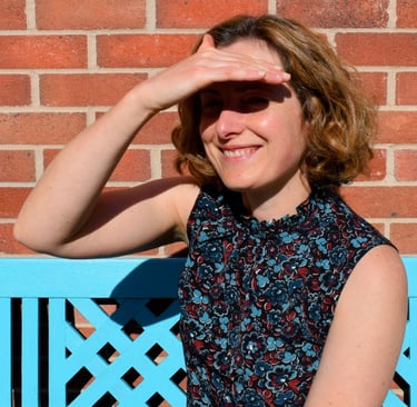 I am looking out past the camera to the garden, smiling, and shading my eyes from the sun