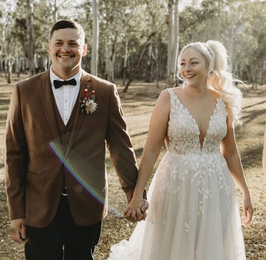 a bride and groom walking down a path in a wooded area