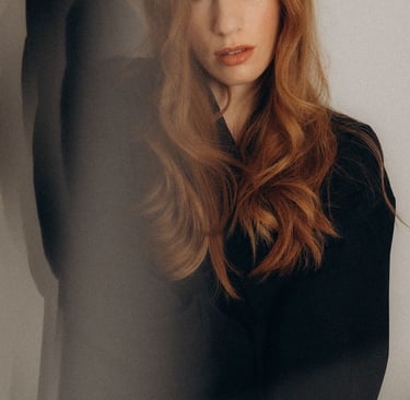 a woman with long red hair and a black top