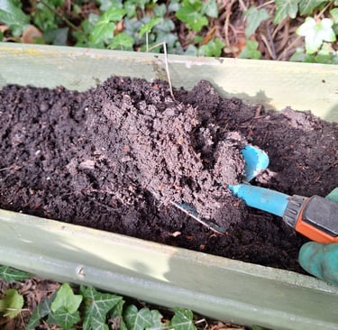 a person that is fertilizing garden bed soil