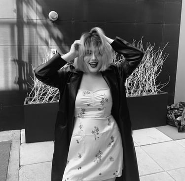 a woman (Angelina Young) in a dress and coat with a coat over her head