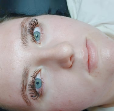 A woman with clear skin showcasing professional eyelash extensions and full lashes.