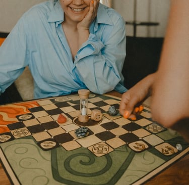a woman sitting at a table with a game board game