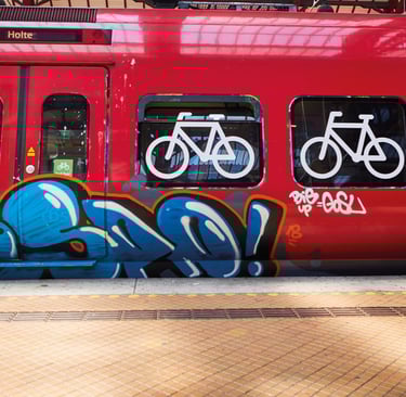 red train with symbols of bicylces at a train station with grafitti on it
