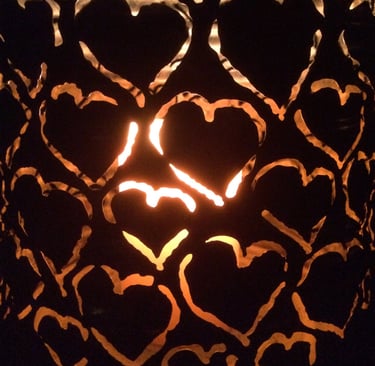 Warmes Kerzenlicht scheint durch Metallherzen und symbolisiert Wärme und Verbindung.