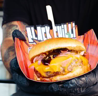 a man holding a large hamburger burger on a paper plate
