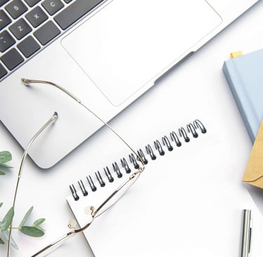 Image of a notebook with a laptop, glasses and eucalyptus leaves