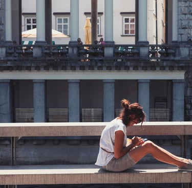 A Woman Sitting on Concrete Bench in Front of a Building in Ljubljana