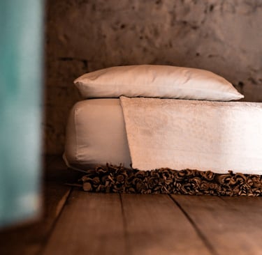 Detail of a bed with white linens in Sardinia, symbol of slow travel and authentic stays