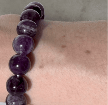 The first half a photo of a wrist with 2 amethyst crystal bracelets on it,this side is the 10mm size