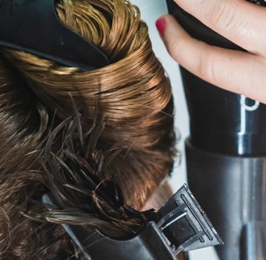 a woman is blow drying her hair in a salon