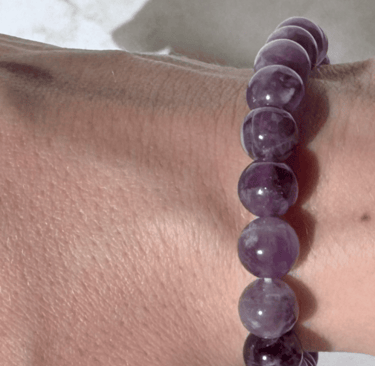 The first half a photo of a wrist with 2 amethyst crystal bracelets on it, this side is the 8mm size