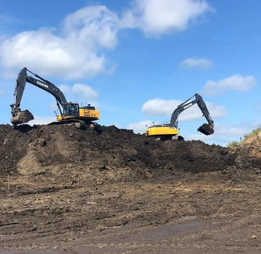 two excavators digging dirt on hill
