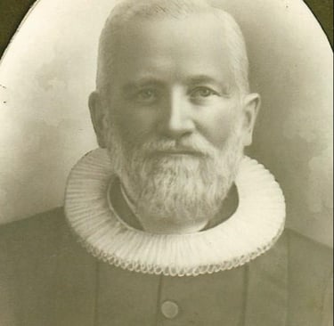 A man with a white ruffled collar and a white beard and mustache, black and white
