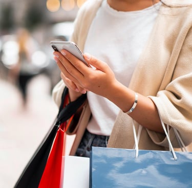 een vrouw die een telefoon vasthoudt terwijl ze een boodschappentas vasthoudt