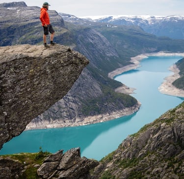 a photo of troltunga mountain in norway with a gree lake