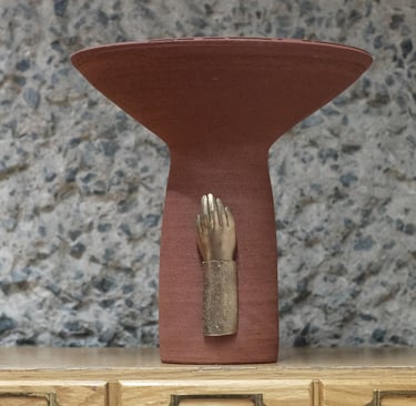 Tall ceramic vessel in deep red stoneware, with a bronze sculpted hand mounted on the base.